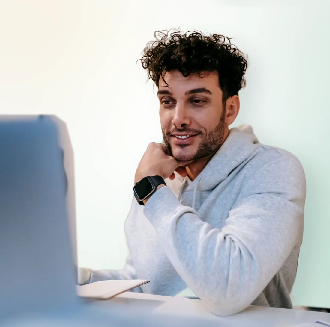 A man smiling at his laptop while he checks his website