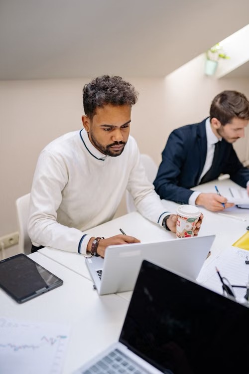 Two people working on laptops at a shared desk